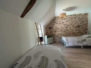 a bedroom with a bed and a brick wall at La Maison de Gautro in Tréhorenteuc