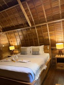 a bed in a wooden room with two lamps at Jordan Guest House in Uluwatu +41 photos