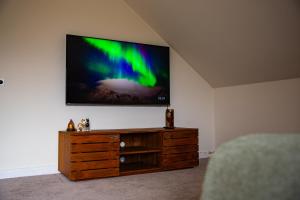 a flat screen tv on a wall above a wooden dresser at Villa Bianca in Dalhem