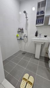 a bathroom with a sink and a shower and two slippers at 대구 수성구 행복의집 