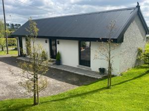 a small house with a black roof and two trees at Glassdrumman Stables in Ballynahinch