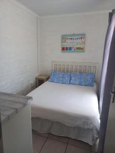 a white bed with blue pillows in a room at Die Waenhuis in Arniston