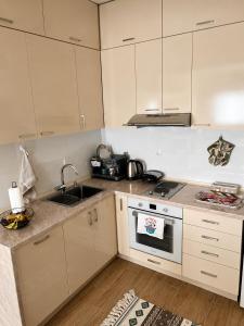 a kitchen with white cabinets and a sink and a stove at Urban Taft Stay Skopje-Modern Vodno View Suite with Private Parking in Taftalidze in Skopje