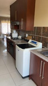 a kitchen with a stove and a dishwasher at Tumi's Home away- 3 Bedroom in eMalahleni