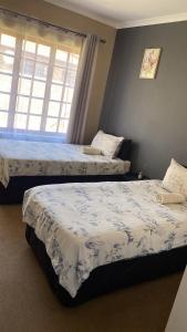 a bedroom with two beds and a window at Tumi's Home away- 3 Bedroom in eMalahleni