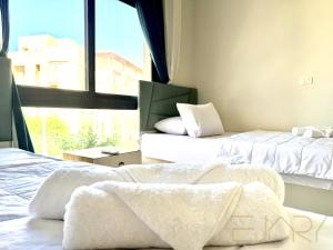 a bedroom with two beds with white sheets and a window at Gaia 2BR First Floor Apartment in El Dab‘a