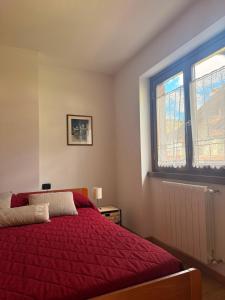 a bedroom with a red bed and a window at Chalet Santa Barbara in Bormio