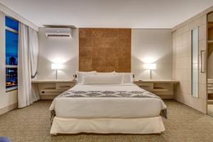 a bedroom with a large bed with two tables and two lamps at K Hotel in Goiânia