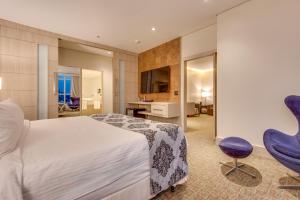 a bedroom with a large bed and purple chairs at K Hotel in Goiânia