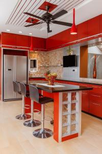 a kitchen with red cabinets and a counter with stools at Luxurious Duplex Villa in Hyderabad
