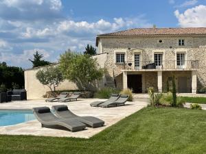a pool with lounge chairs in front of a house at Domaine Chamarel in Saint-Paulet-de-Caisson