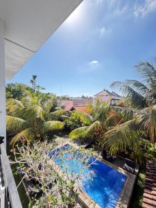 an open balcony with a pool and palm trees at Jordan Guest House in Uluwatu