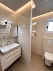 a bathroom with a white sink and a toilet at Apartman Šarić in Neum +7 photos