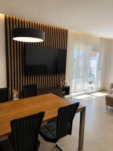 a dining room with a table and chairs and a television at Apartman Šarić in Neum