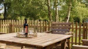 a wooden picnic table with a bottle of wine and glasses at Paddock Cottage in Winchcombe