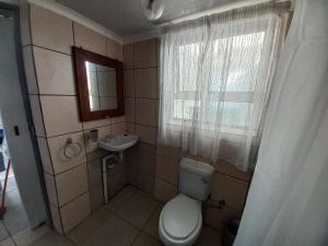 a bathroom with a toilet and a sink and a window at Die Waenhuis in Arniston +11 photos