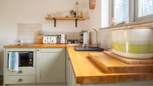 a kitchen counter with a large bowl on a cutting board at Paddock Cottage in Winchcombe +16 photos