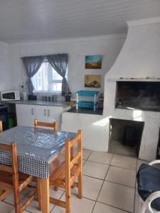 a kitchen with a table and chairs and a fireplace at Die Waenhuis in Arniston