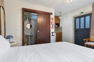 a bedroom with a white bed and a wooden door at Casa do Monte - Monção in Poças do Monte