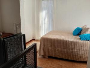 a bedroom with a bed with blue pillows on it at Oro y Miel II en pleno centro de Chascomús in Chascomús