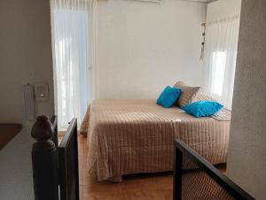a bedroom with a bed with blue pillows on it at Oro y Miel II en pleno centro de Chascomús in Chascomús