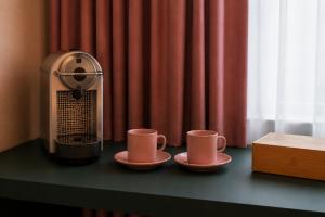 two cups on a table next to a coffee machine at Hôtel Les Loges in Geneva