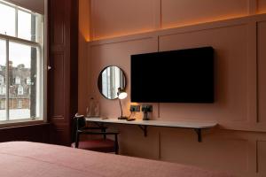a bedroom with a desk with a television on a wall at The Address Wren in Glasgow