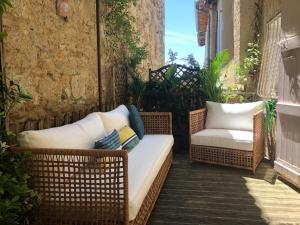 two wicker chairs and a couch on a balcony at À Plus, Lectoure in Lectoure