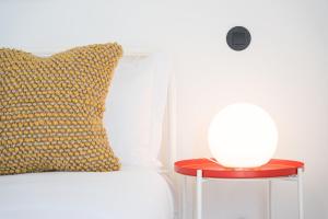a bed with a pillow and a red table with a lamp at GuestReady - Freixo Apartments in Porto