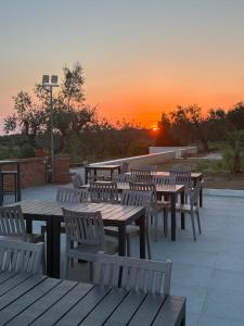 a group of tables and chairs with a sunset in the background at Oliveta del Tabernacolo in Malmantile