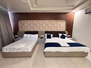 a bedroom with two beds with blue and white pillows at Hotel Golden Heights in Ajmer