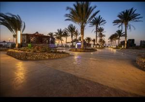 a parking lot with palm trees and a building at Nozha Beach للعائلات in Ras Sedr