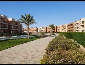 a walkway with a palm tree and some buildings at Nozha Beach للعائلات in Ras Sedr +45 photos