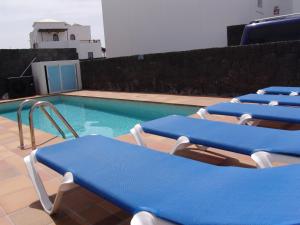 a swimming pool with blue lounge chairs next to it at Casa Fama con piscina privada clima in Yaiza