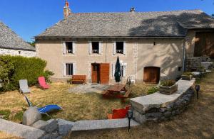 a house with a yard with chairs and a table at Le Refuge de l'Argence in Alpuech