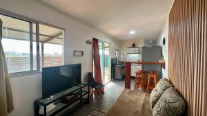 a living room with a flat screen tv and a kitchen at Aurora in Carmelo
