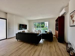 a living room with a black couch and a table at Villa Las Dos Rocas in Calonge