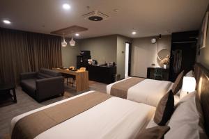 a hotel room with two beds and a desk at Hotel Valya Melaka Sentral Riverfront in Malacca