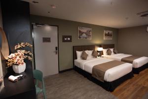 a hotel room with two beds and a table with flowers at Hotel Valya Melaka Sentral Riverfront in Malacca +123 photos