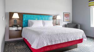 a bedroom with a large bed with a blue headboard at Hampton Inn Chelsea, Mi in Chelsea