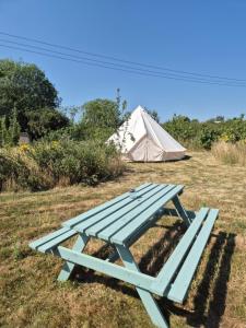 a picnic table with a tent in the background at Lyng Farm Campsite in Brisley