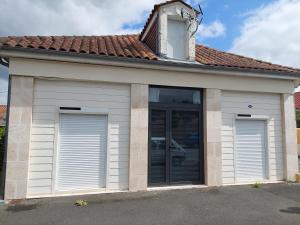 a building with two garage doors and a roof at Maison Origine Périgueux in Périgueux