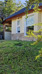 a house with a garage and a grass yard at Cabañas Mateo in Villa Pehuenia