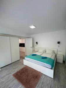a white bedroom with a large bed with blue sheets at BB Riviera Resort in Balatonboglár