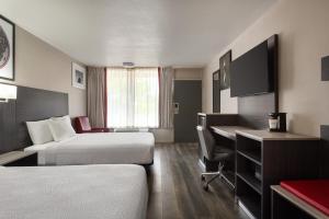 a hotel room with two beds and a desk at Ramada by Wyndham Cocoa in Cocoa