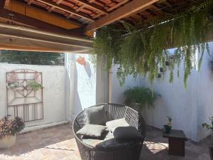 a wicker chair sitting on a patio with plants at Hospedagem da Néli in Aparecida