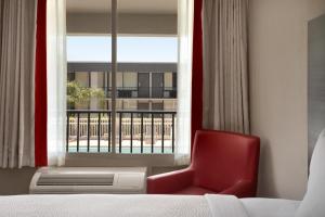 a red chair sitting in front of a window at Ramada by Wyndham Cocoa in Cocoa +53 photos