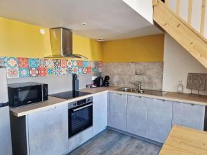 a kitchen with stainless steel appliances and yellow walls at Retro Chic in Saumur +5 photos