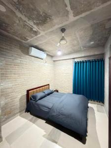 a bedroom with a bed and a blue curtain at HomeWay Dhaka in Kāmarpāra