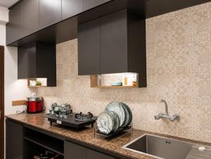 a kitchen with black cabinets and a sink at HomeWay Dhaka in Kāmarpāra